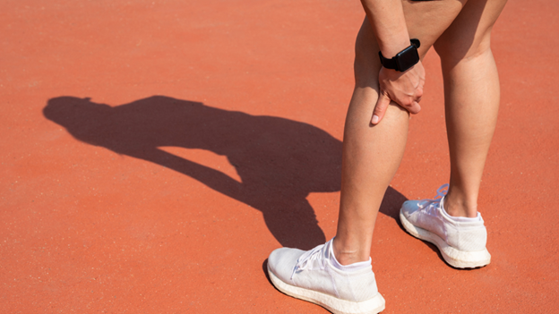 woman grasping her leg after a hamstring strain during physical activity