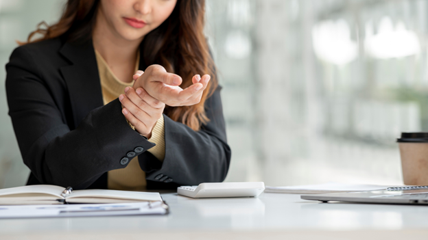 Woman grasping her hand while experiencing carpal tunnel syndrome symptoms