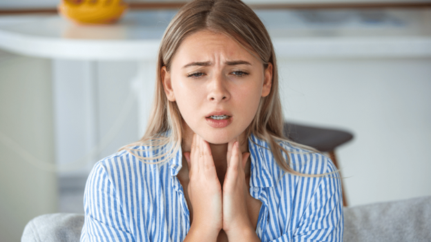 Woman touching her throat, experiencing tonsillitis symptoms