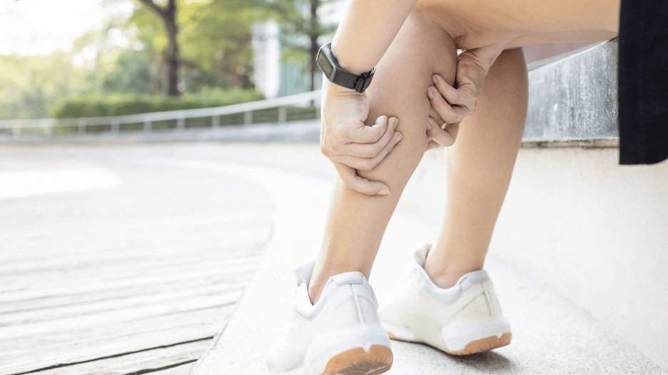 Person grasping their leg during a heat cramp