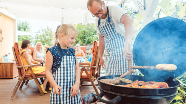 Father and daughter grilling safely together on outdoor barbecue grill during family cookout