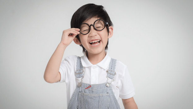 Child in school clothes wearing prescription glasses for pediatric eye care and safety