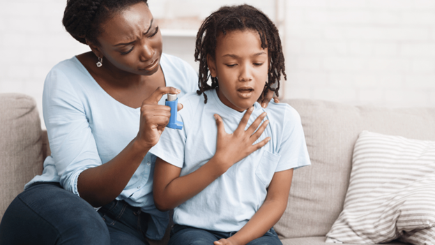 Parent helping child use asthma inhaler during breathing difficulty episode